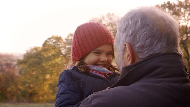 Grandfather Walking With Granddaughter In Autumn Countryside