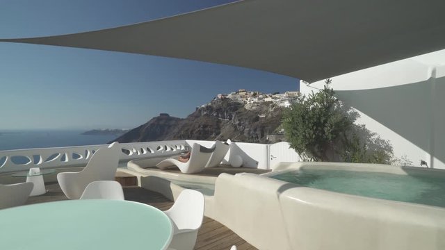 4k travel video luxury terrace of hotel suite with honeymoon couple relaxing in sun lounger high above on santorini island