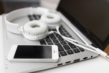 Laptop with headphones and mobile phone close-up