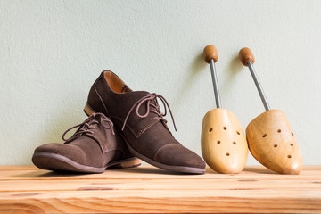 Men's accessories, vintage shoes and wooden shoe tree on wooden table over white wall background