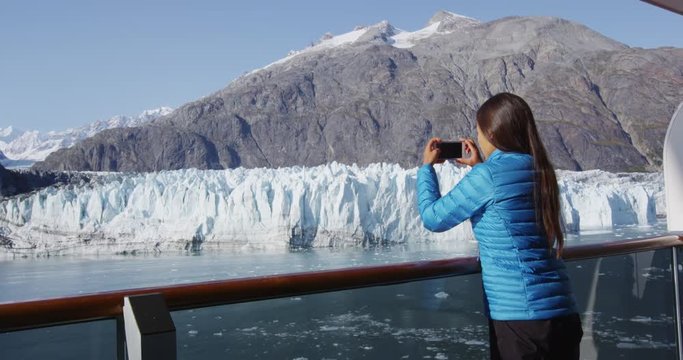 Tourist on Alaska cruise ship taking photo of glacier in Glacier Bay National Park, USA. Woman taking picture using smart phone on travel vacation. Margerie Glacier. RED EPIC SLOW MOTION.