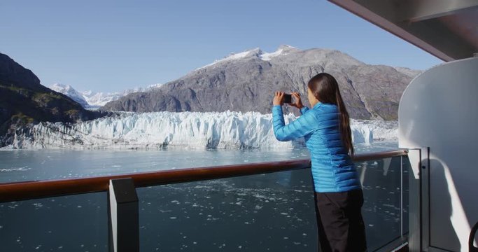 Alaska cruise ship passenger photographing glacier in Glacier Bay National Park, USA. Woman tourist taking photo picture using smart phone on travel vacation. Margerie Glacier. RED EPIC SLOW MOTION