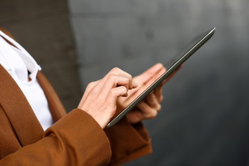 Businesswoman with tablet computer standing outside of an office building.