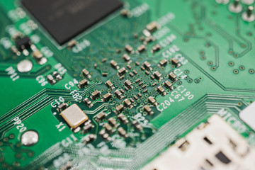 Green circuit board with small capacitors, resistors and microchips for electronic engineering.