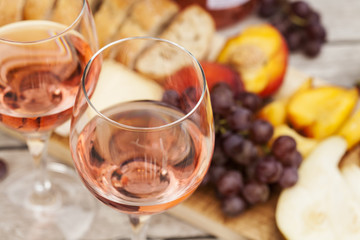 Two glasses of rose wine and board with fruits, bread and cheese on wooden table, shallow DOF - 173198002