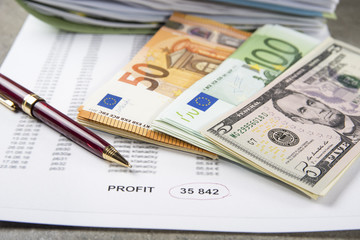 Profit and loss concept image of a pen, calculator and coins on financial documents.