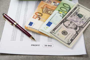 Profit and loss concept image of a pen, calculator and coins on financial documents.