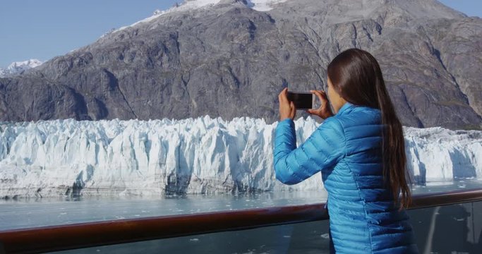 Glacier Bay Alaska cruise ship passenger photographing Margerie Glacier in Glacier Bay National Park, USA. Woman tourist taking photo picture using phone on travel vacation. RED EPIC SLOW MOTION