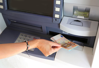 hand of young woman while withdrawing banknotes from an ATM in e