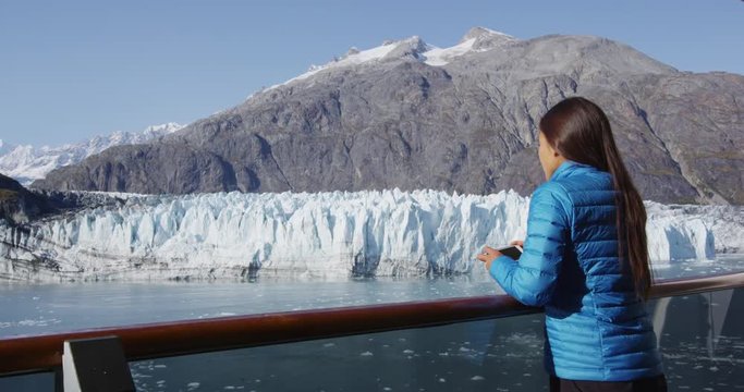 Alaska cruise ship passenger taking photo of glacier in Glacier Bay National Park, USA. Woman tourist taking picture using smart phone on travel vacation. Margerie Glacier. RED EPIC SLOW MOTION.