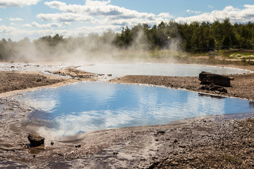 Hot spring in the volcanic landscape around the Strokkur geyser in Iceland, a famous area with many geological features.