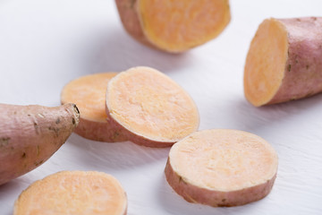 Closeup of raw sweet potato on white table. Slices.