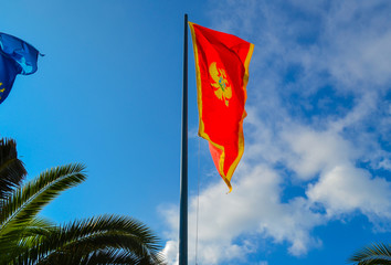 Montenegrin red flag with a two-headed eagle, against a blue sky