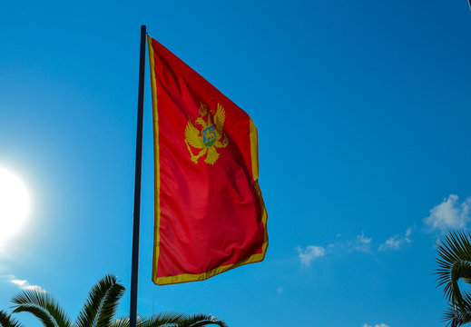Montenegrin red flag with a two-headed eagle, against a blue sky