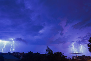 Storm clouds with lightning strike bolts passing over night city of Bangkok cityscape. 