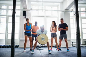 People cheering on their friend lifting weights in a gym