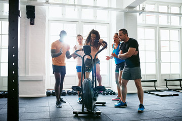 Cheering people supporting their friend riding a gym stationary