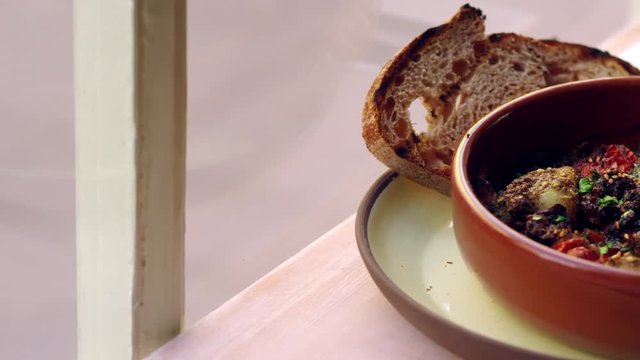 Cod and chorizo bake with sourdough bread by window, pan