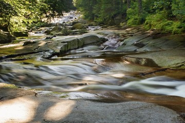 Water flows over stones in mountain river.