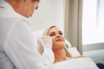Female doctor doing botox injections on a mature client's face