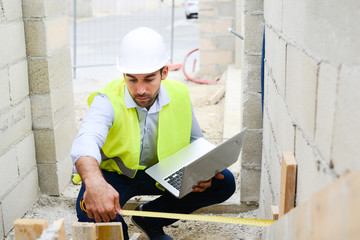 handsome young man foreman architect supervising a new house construction site