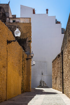 A small alleyway in the coastal city of vinaros spain with an old statue at the end