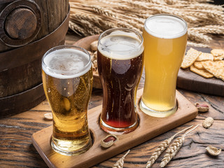Glasses of beer and snacks on the wooden table.