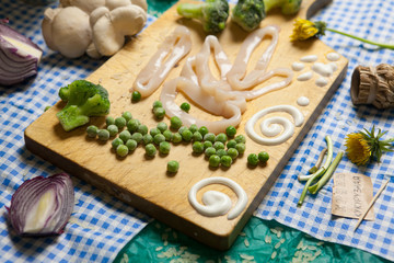 Frozen peas, broccoli and  fresh squid rings on wooden cutting board