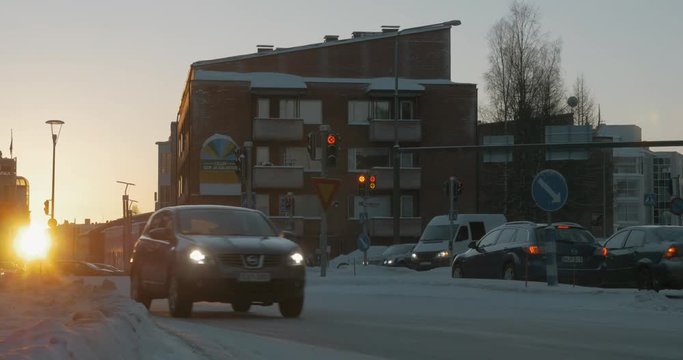 ROVANIEMI, FINLAND - JANUARY 06, 2017: Scene of winter town at sunset. Car traffic on snowy roads and vehicles making a stop on red traffic lights