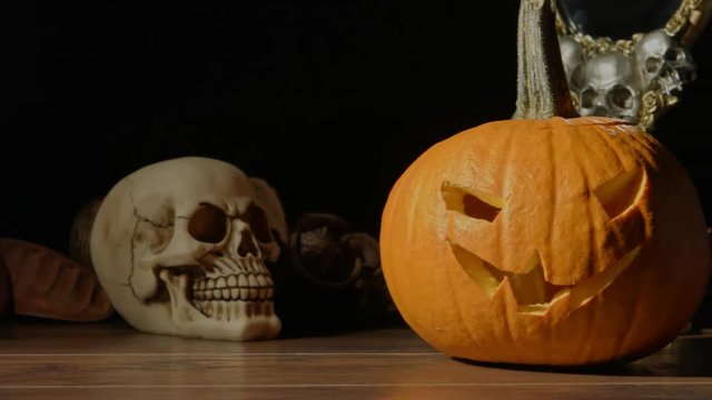 Carved Halloween pumpkin lights inside with flame and skuls around.