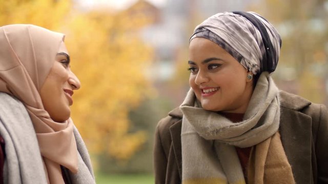 Two British Muslim Women Meeting In Urban Park 