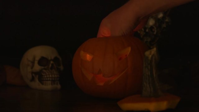 Carved Halloween pumpkin lights inside with flame and skuls around.