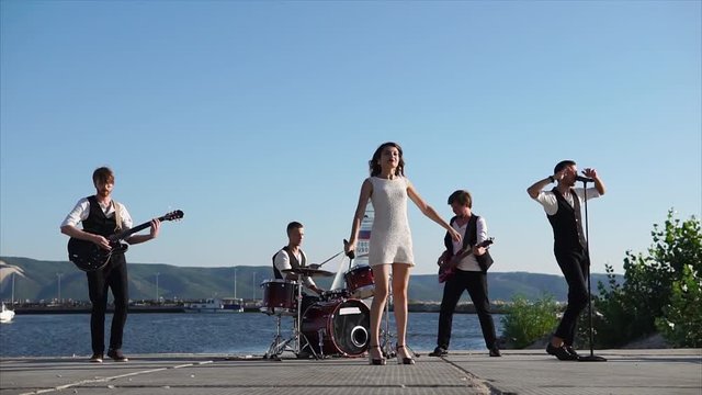 group Young musicians perform at the pier, men and women perform a musical composition in the daytime, sympathetic soloists perform at a street concert