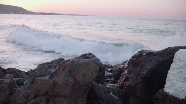 Beautiful dramatic skies and amazing sunrise over the beach in Creete, Greece. Mediterranean sea waves crash into rocks at dusk in slow motion.