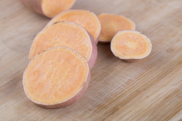 Raw sweet potato on wood background. Closeup.