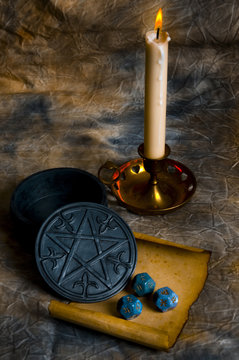 Esoteric concept with astrology cubes, a candle, magic pentagram  and mystic occult pergamen 
