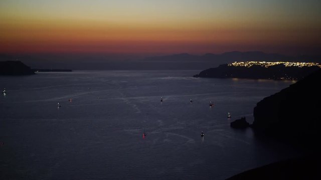 4k travel video caldera of santorini island with tiny boats and illuminated oia village after sunset
