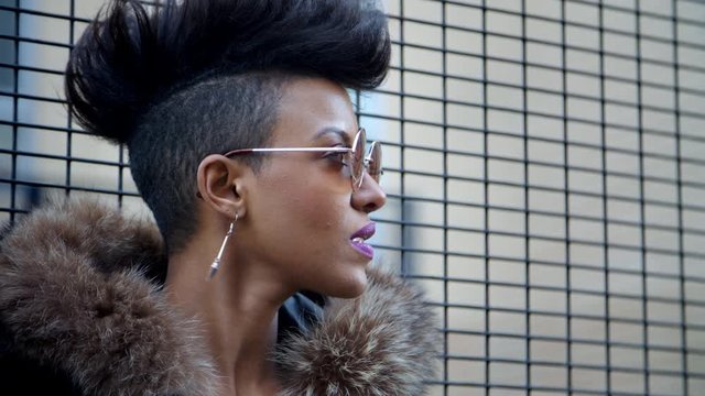 Stylish Fashion Blogger Stands By Fence In Urban Street