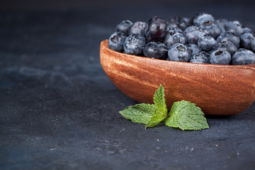 Fresh blueberries with a leaf of mint in the heart-shaped bowl