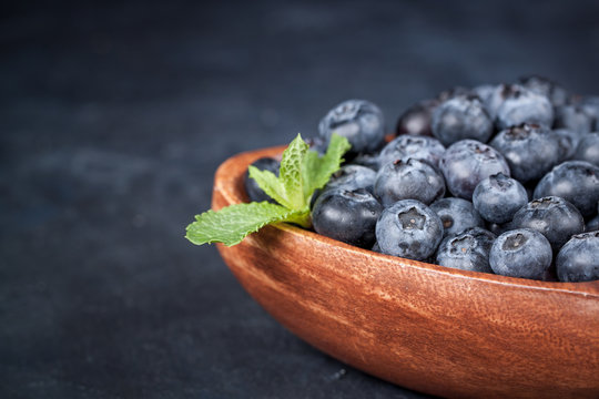 Fresh blueberries with a leaf of mint in the heart-shaped bowl