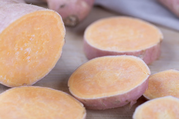 Raw sweet potato on wood background. Slices.