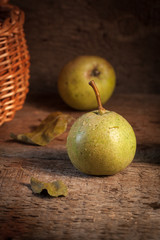 Two green pears in evening light near the basket