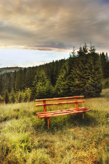 Obraz premium Wooden bench in the mountain meadow. Rural landscape