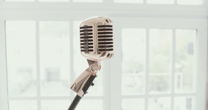 Vintage microphone against a window. white background . Slow motion.