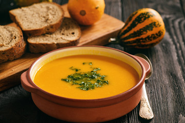 Homemade pumpkin cream soup on black background.