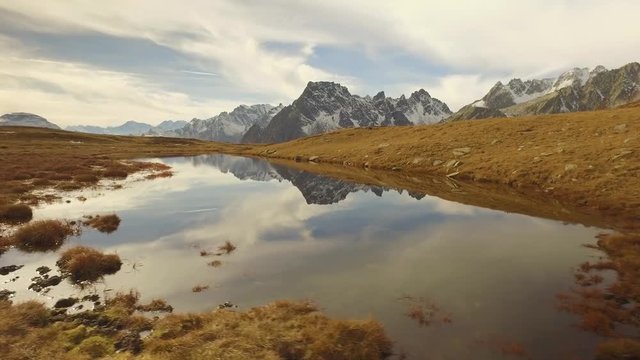 side POV walking on fall valley lake and snowy mounts approaching sunset.Sunny autumn day Hiking in colorful red forest wild nature mountain outdoors.Alps Devero.4k point of view establishing video