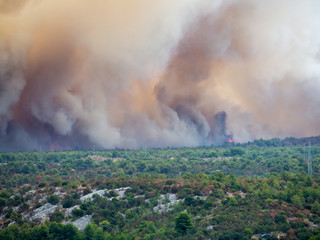 Forest fire in Croatia, summer natural disaster close to national park Krka, Sibenik region, boats and yachts escaping Skradin town from the smoke