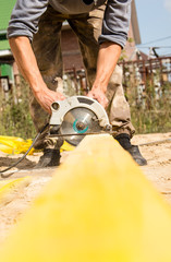 worker saws a wooden plank at a construction site