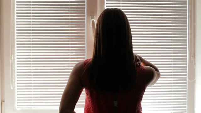 woman take off dress. sexy female undresses at a window. silhouette of the undressing woman. woman undresses in the office