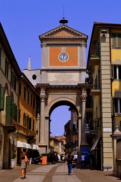 Main street in an Italian city Chieri. The photo shows colorful buildings, a historical arch and pedestrians walking along the street.
